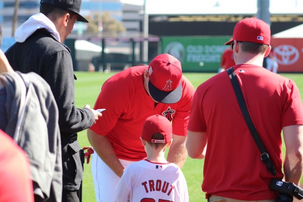 Angels superstar Mike Trout signs a ball for a young fan.